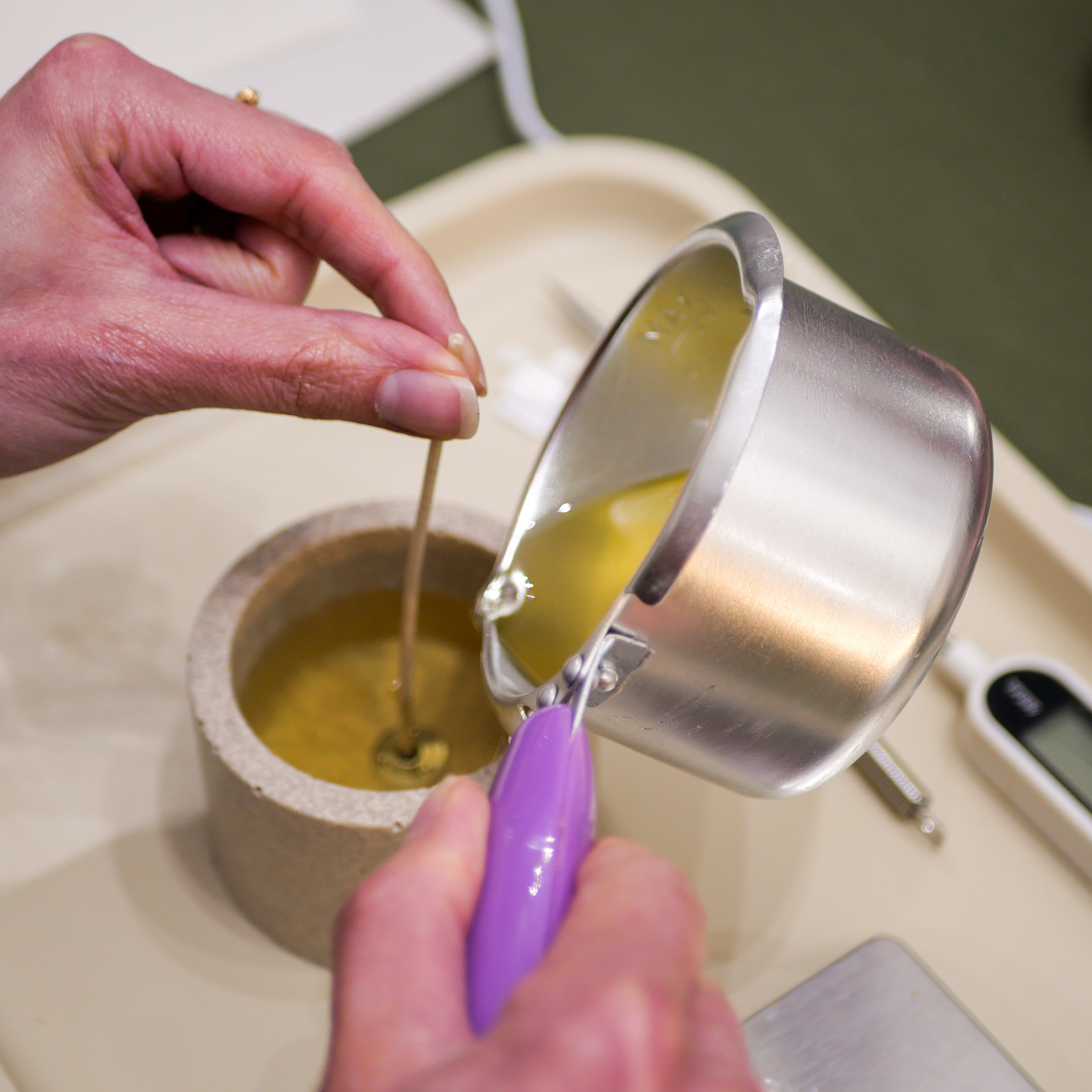 Participant en train de couler la cire végétale lors d'un atelier DIY bougie à La Rochelle.